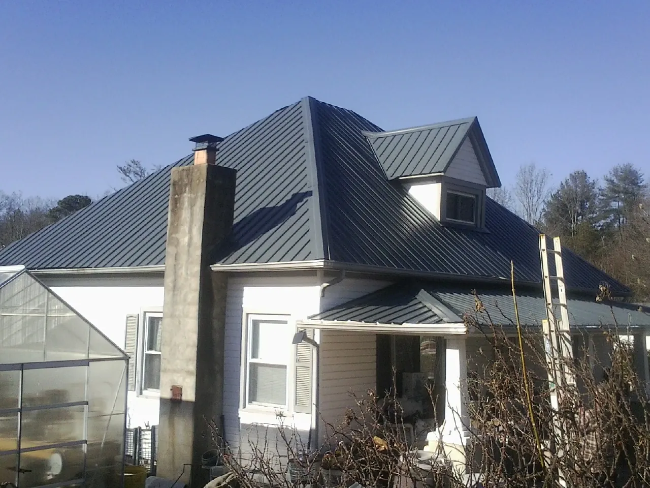 Dark blue standing seam metal roof on a white farmhouse with dormer — Slate & Tile Roof Repair by Roofing Brothers in Columbia Cross Roads