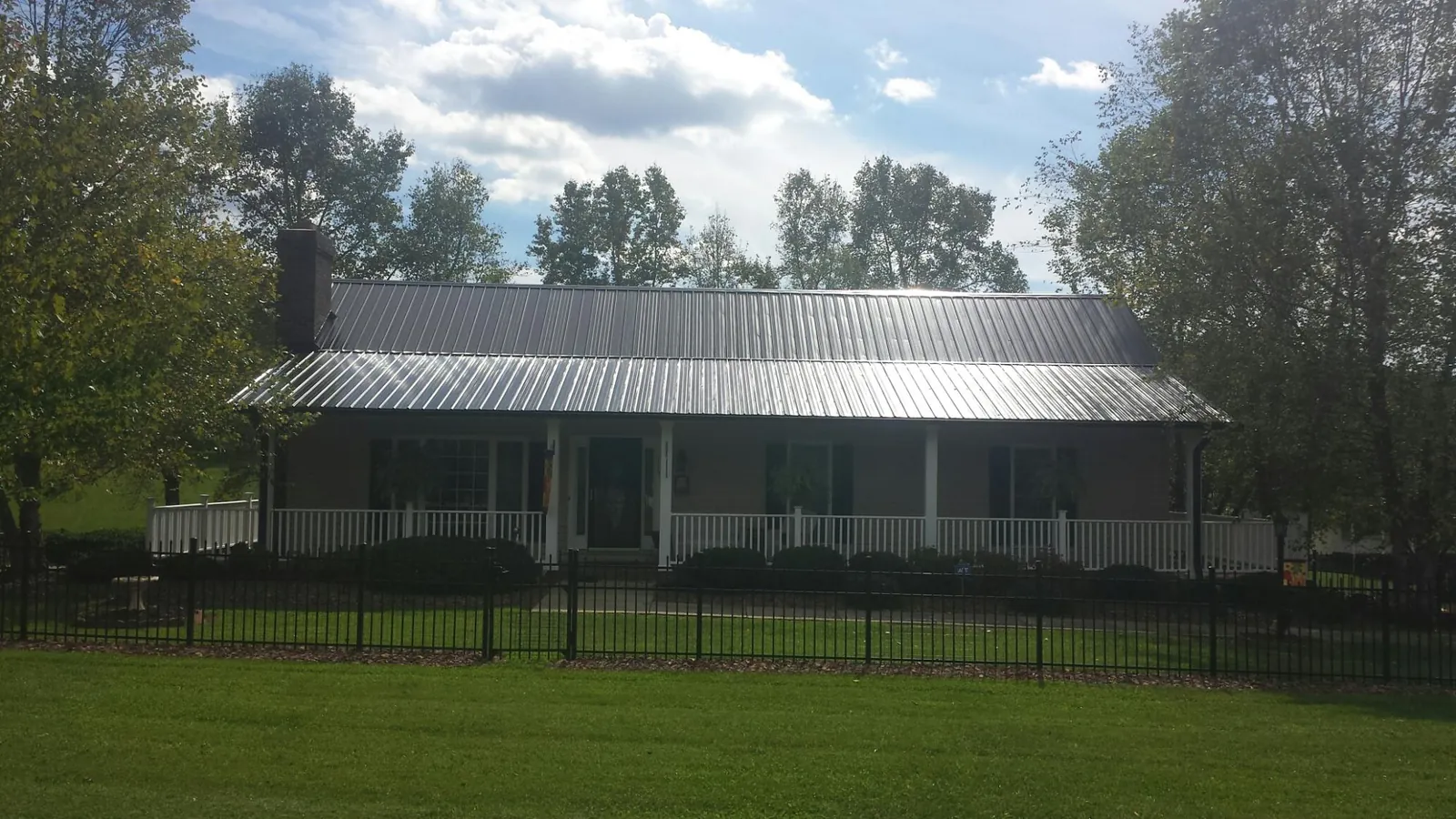 Gray metal roof on a brick ranch with a full width front porch — Gutter Guard Installation work by our crew in Columbia Cross Roads