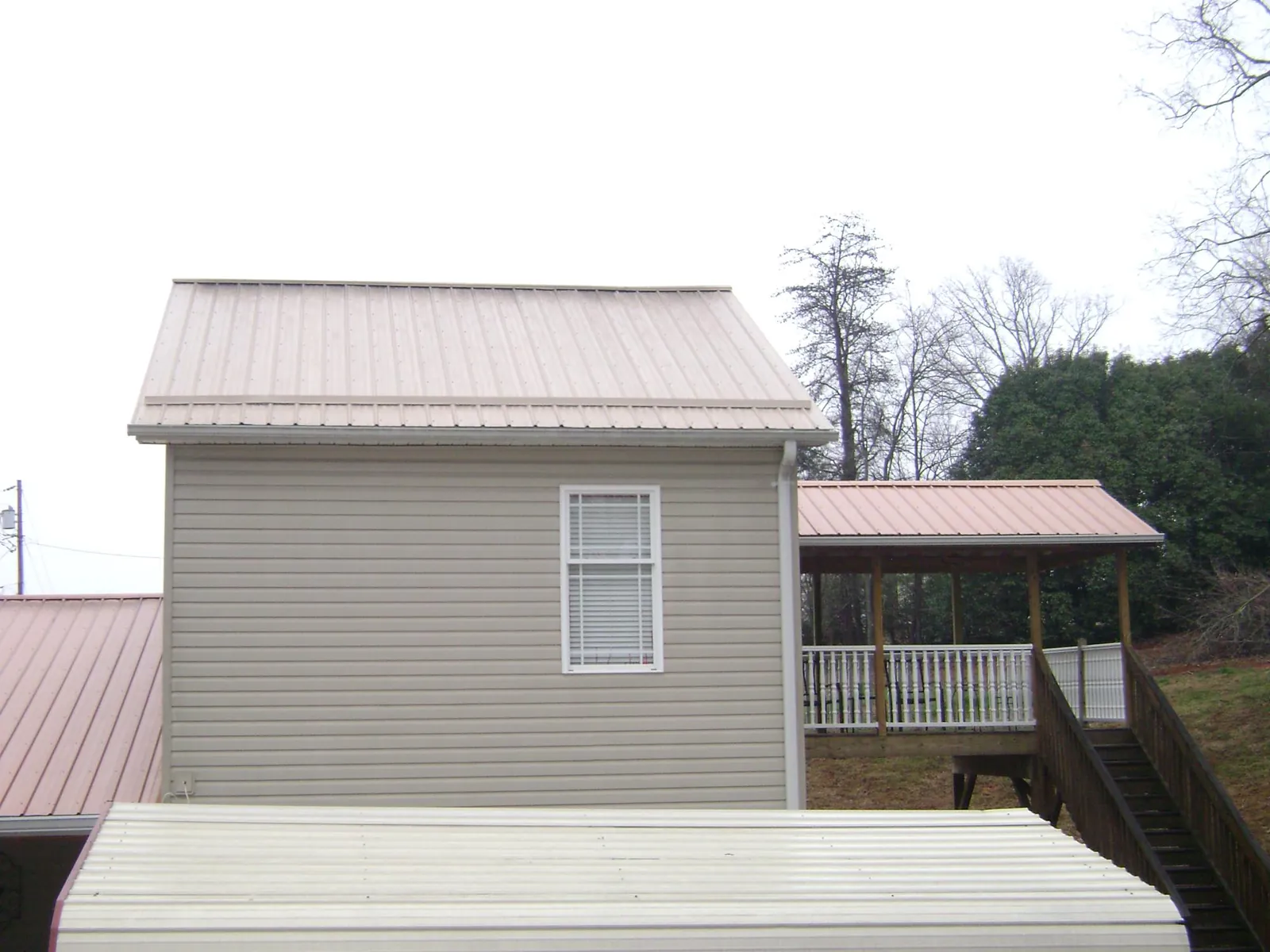 Tan metal roofs on a two story addition and attached porch, from a Roof Replacement job in Columbia Cross Roads