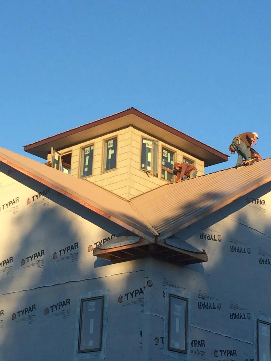 Roofers working around a rooftop cupola on a new metal roof at sunset — Roof Waterproofing in Columbia Cross Roads by Roofing Brothers